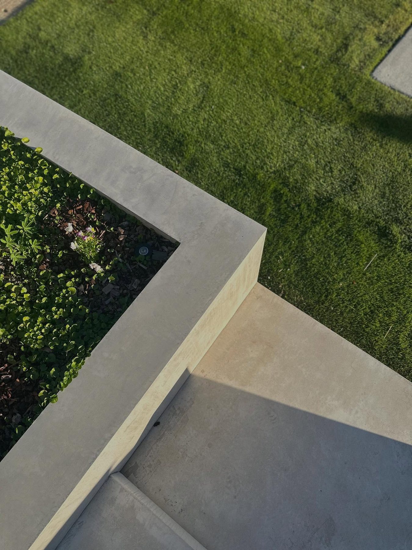 Aerial view of a completed landscape showing concrete paths, planted beds and turf laid out in geometric bands